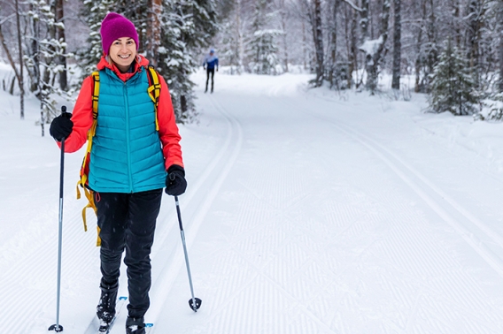 Woman cross country skiing in the snow and smiling.